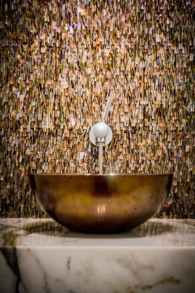Luxury bathroom with bronze vessel sink and marble tile wall