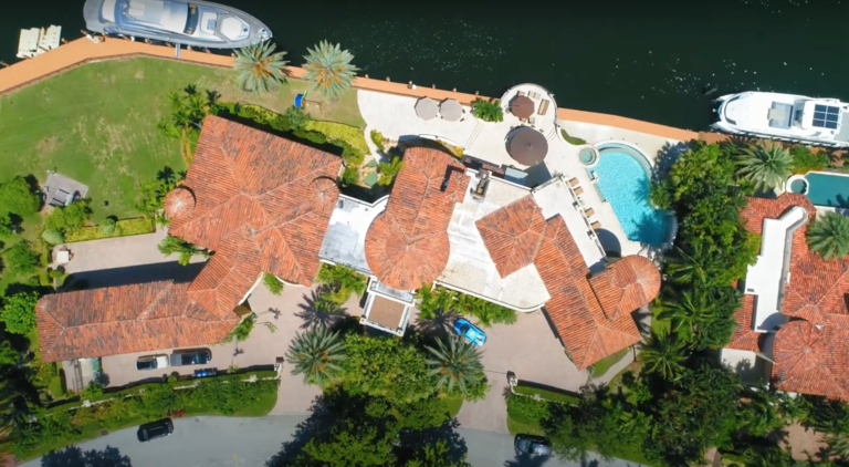 Aerial view of luxury waterfront estate with pool and boats on canal