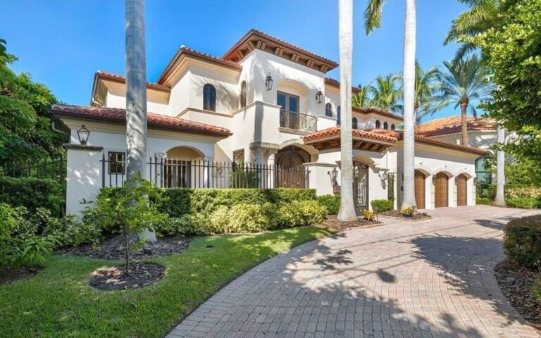 Aerial view of waterfront mansion with cream stucco and city skyline