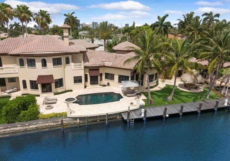 Aerial view of waterfront Mediterranean mansion with pool and dock