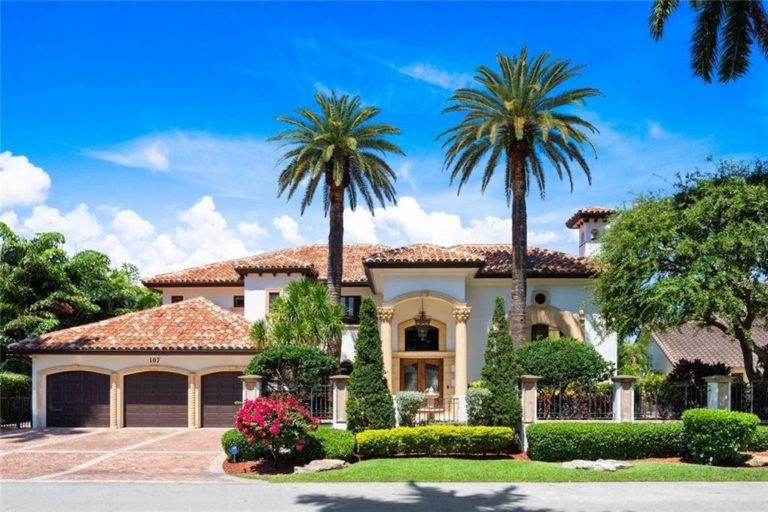 Mediterranean villa with palm trees and brick driveway in South Florida