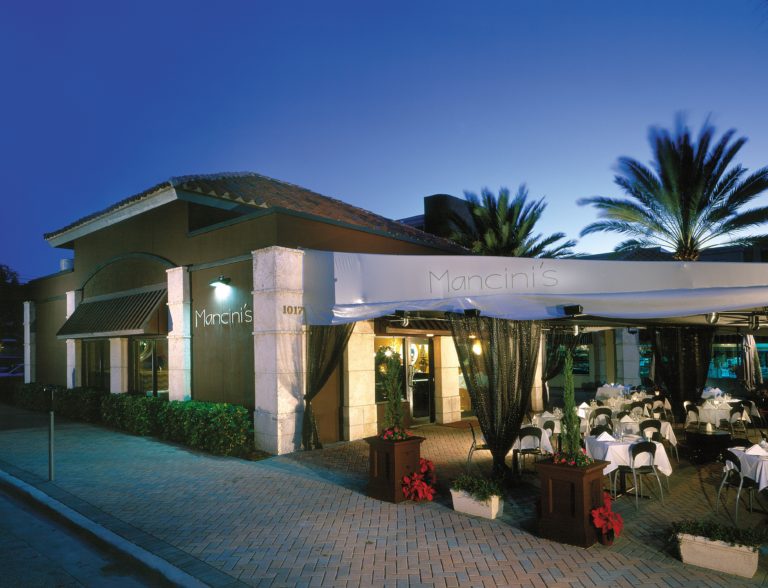 Elegant beachfront restaurant at dusk with white stone and palm trees