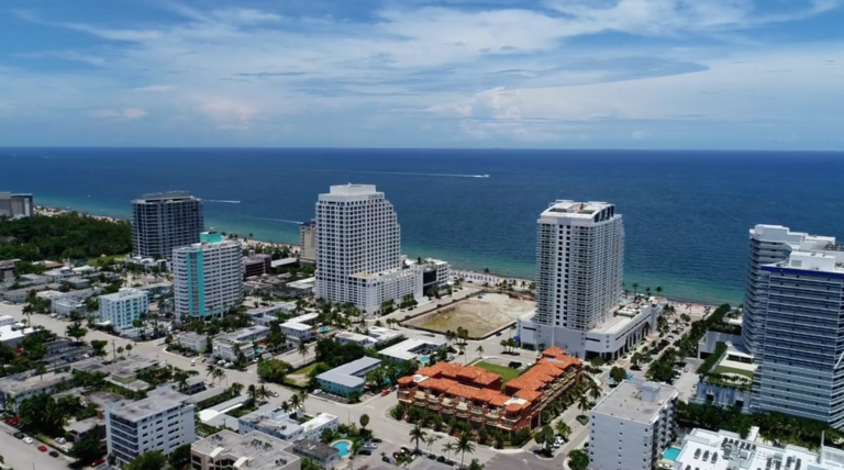 Aerial view of beachfront coastal city with high-rise buildings and turquoise ocean